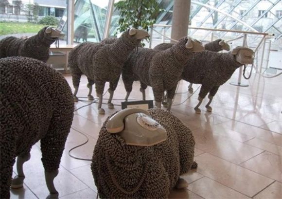 Exposição de ovelhas feitas com telefones antigos reciclados.